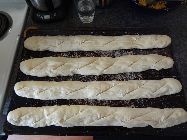 Baguettes placed on the baking sheet and scored with a knife
