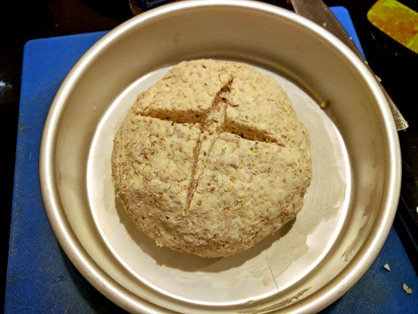 Soda bread dough shaped into a loaf with cross-cut
